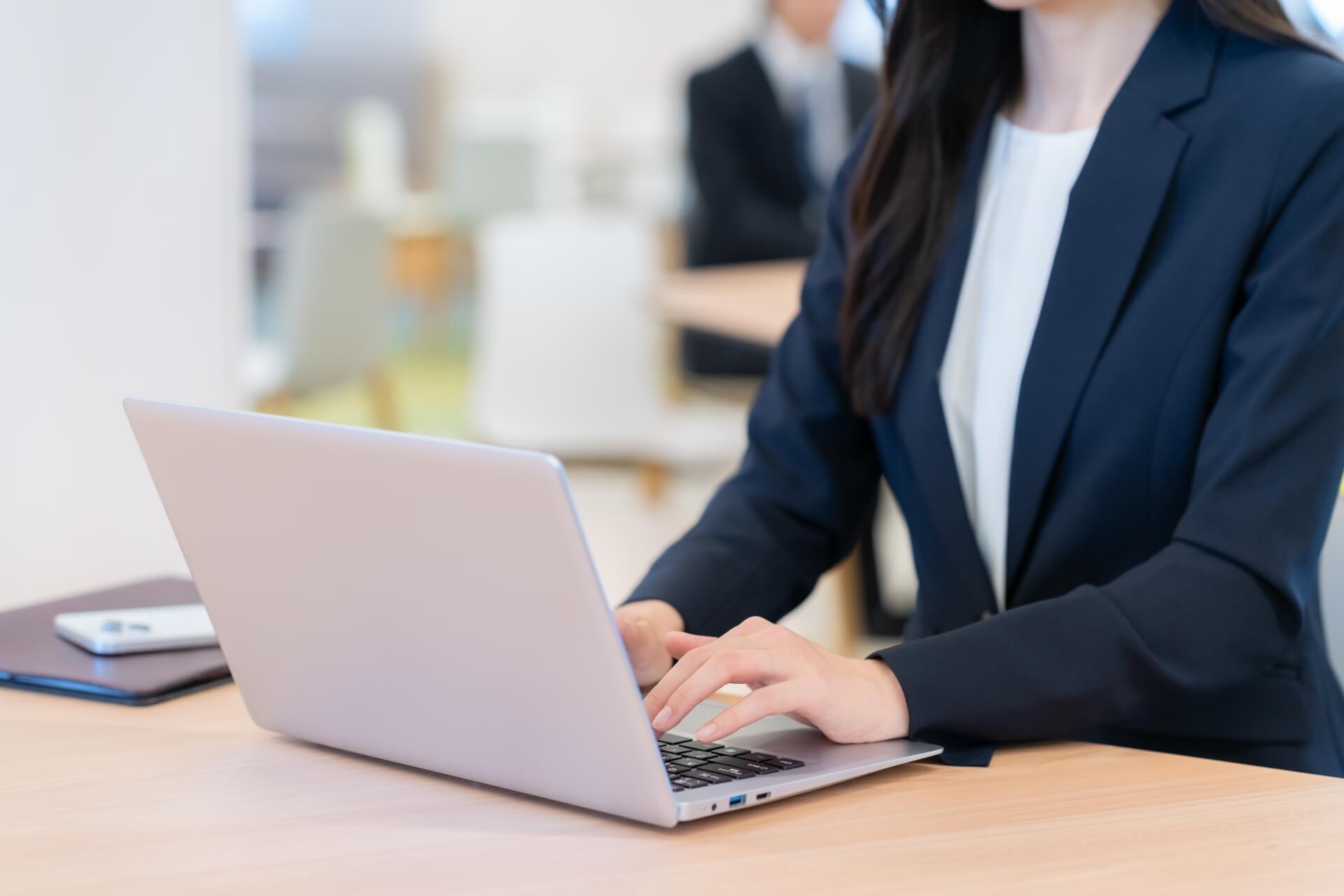 スーツの女性がノートPCを操作中